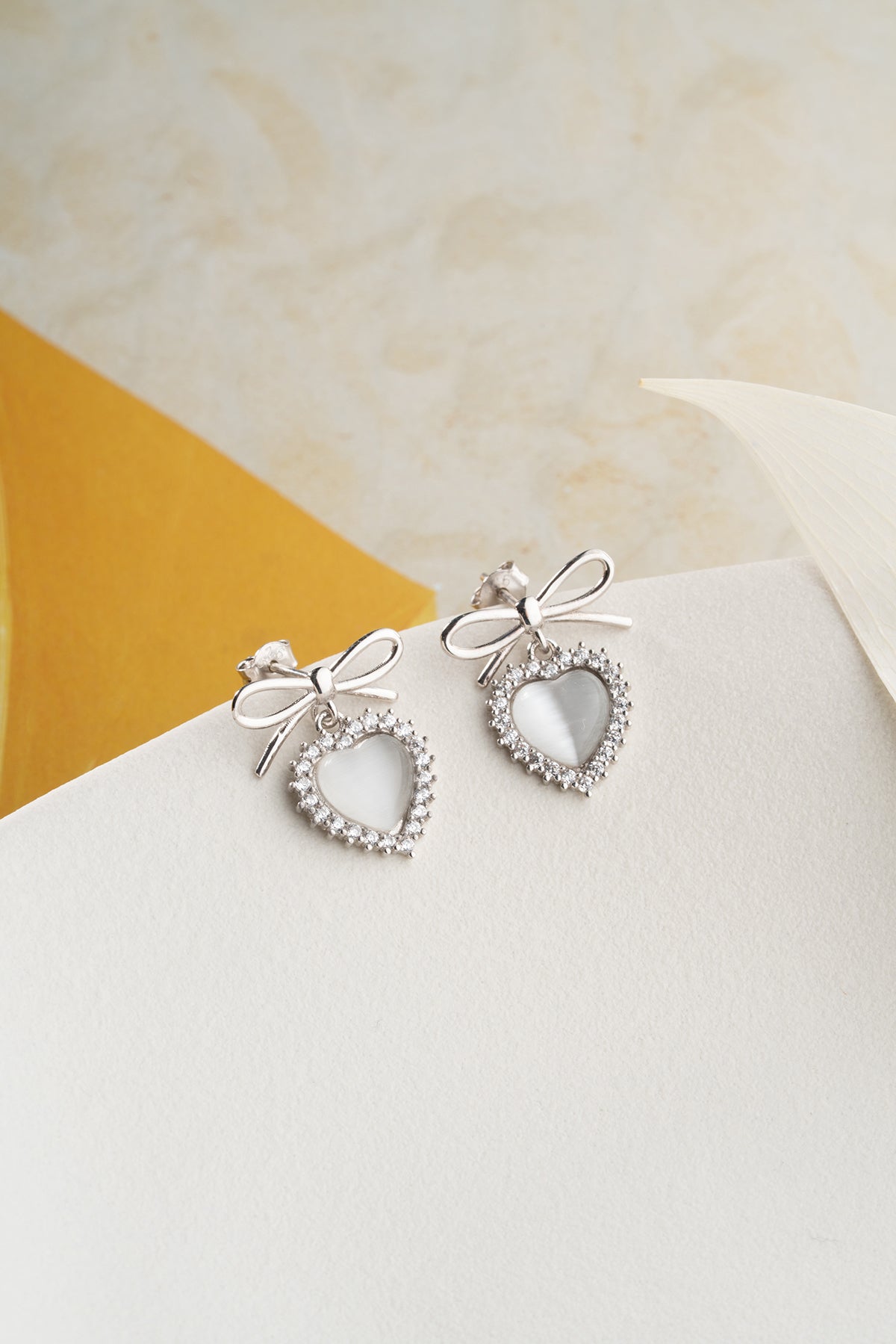 Silver earrings with heart and bow detail