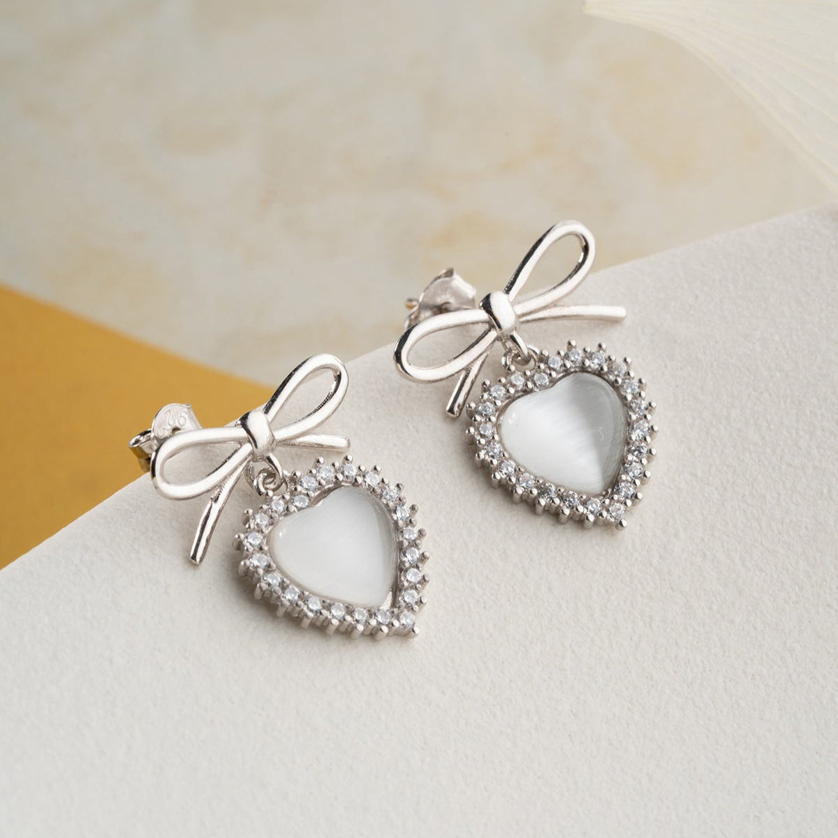 Silver earrings with heart and bow detail